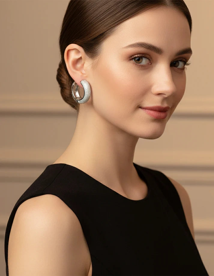 Woman wearing silver hoop earrings with a neutral background