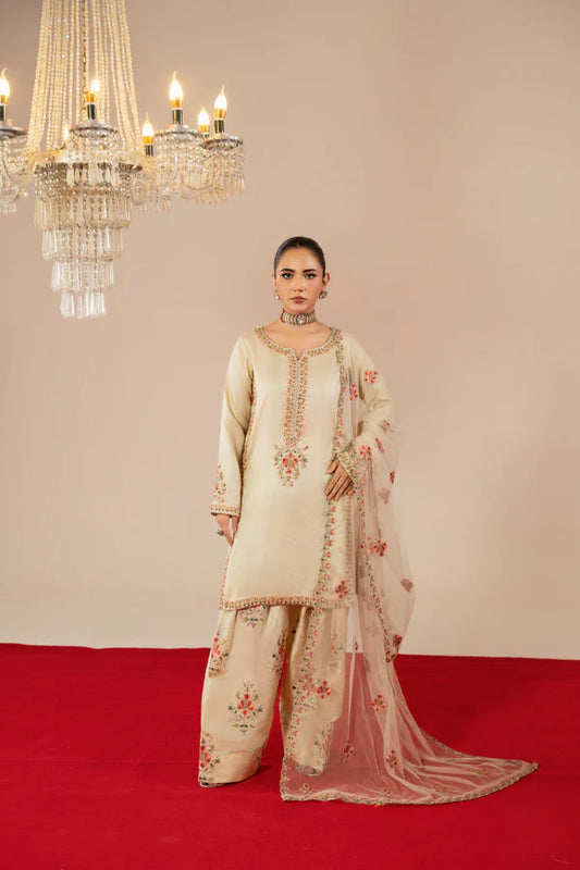 Woman in a traditional outfit standing on a red carpet with chandeliers in the background