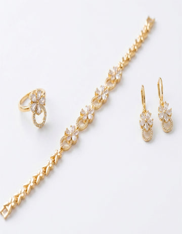 Gold jewelry set with bracelet, ring, and earrings on a white background