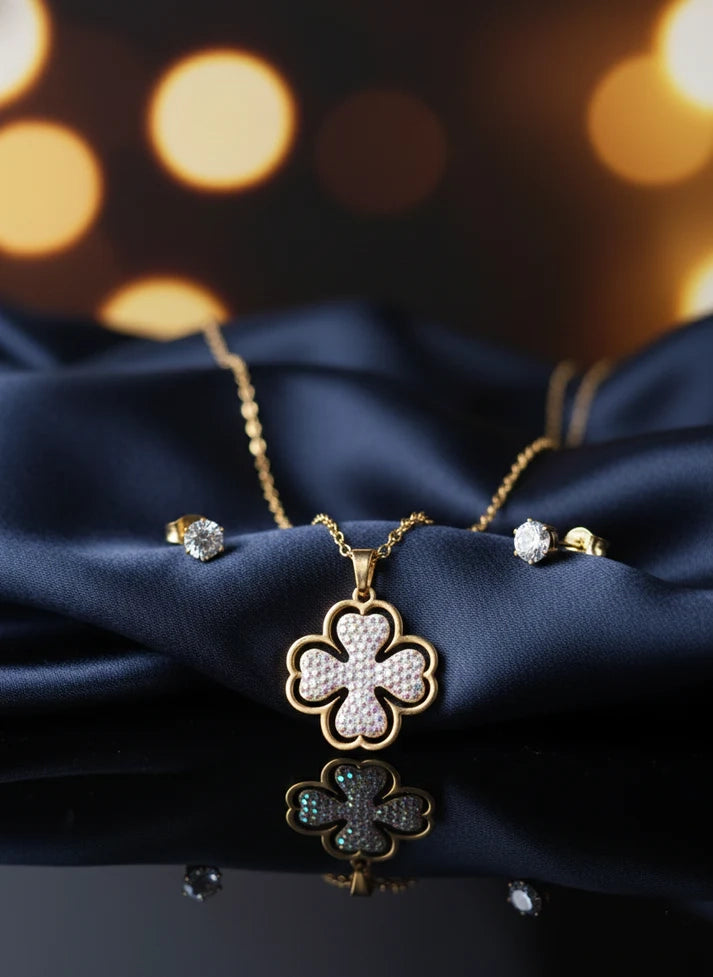 Gold necklace with clover design and matching earrings on a dark 