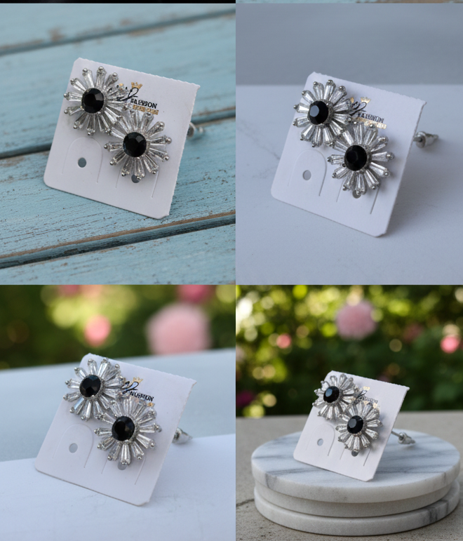 Silver floral earrings with black centers on a white card, displayed on a blue wooden surface and marble stand.