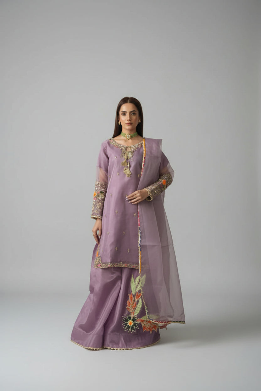Woman in a purple traditional outfit standing in a room with decorative elements.