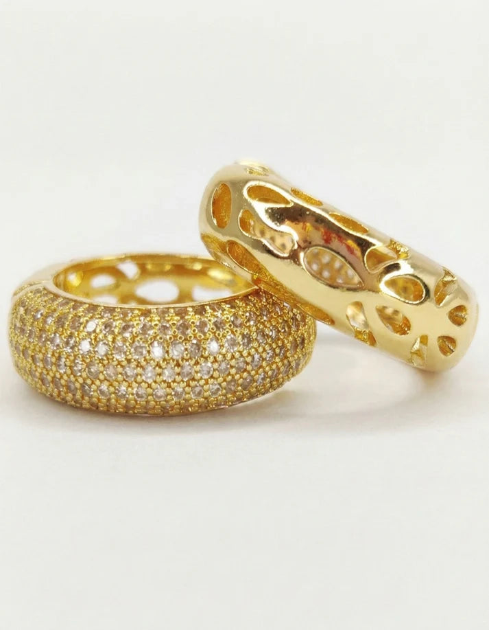 Two gold rings with intricate designs on a light gray background