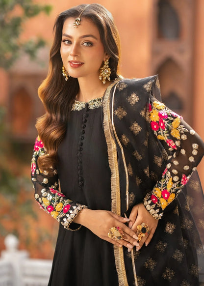 Woman in traditional outfit with floral embroidery against a blurred architectural background