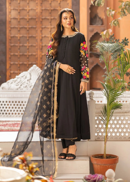 Woman in a black traditional outfit with floral embroidery standing in an outdoor setting.