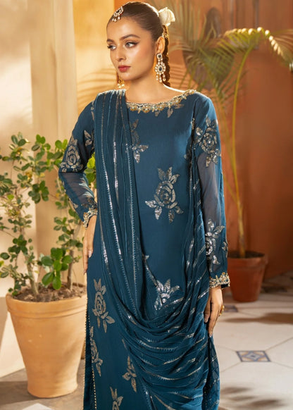 Woman wearing a blue embroidered dress in an indoor setting with plants.