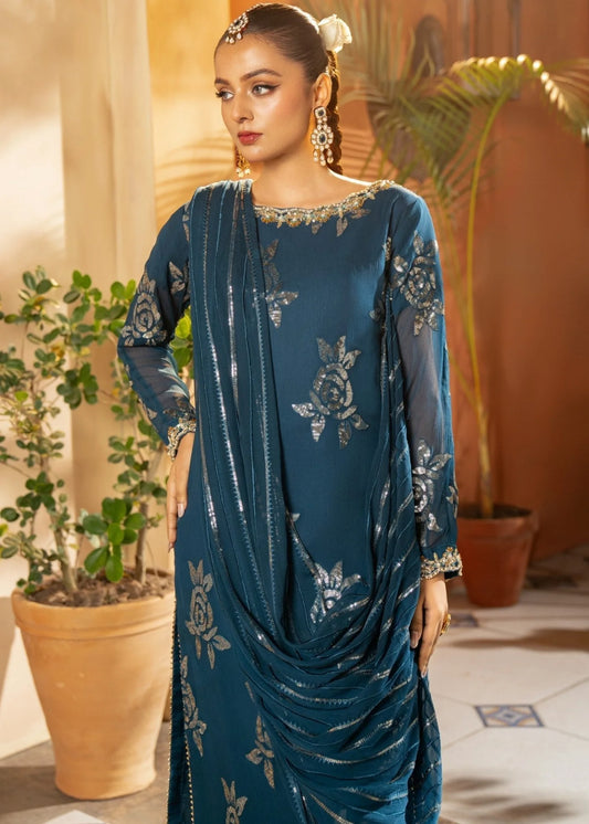 Woman wearing a blue embroidered dress in an indoor setting with plants.