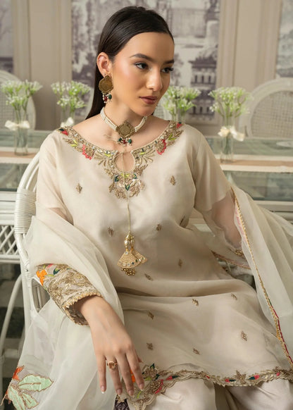 Woman in a traditional outfit with intricate embroidery sitting in an elegant room.