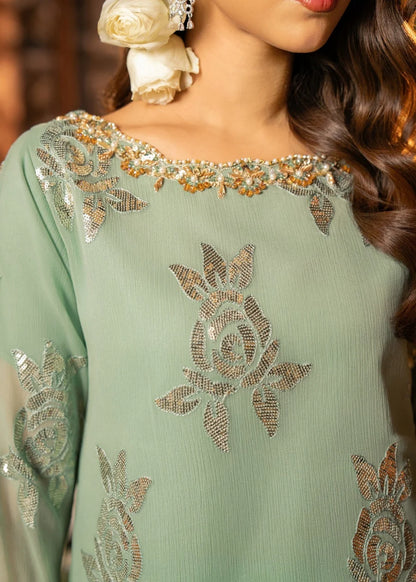 Close-up of a person wearing a light green embroidered outfit with gold details.