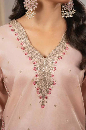 Close-up of a pink embroidered blouse with floral patterns and pearl earrings.