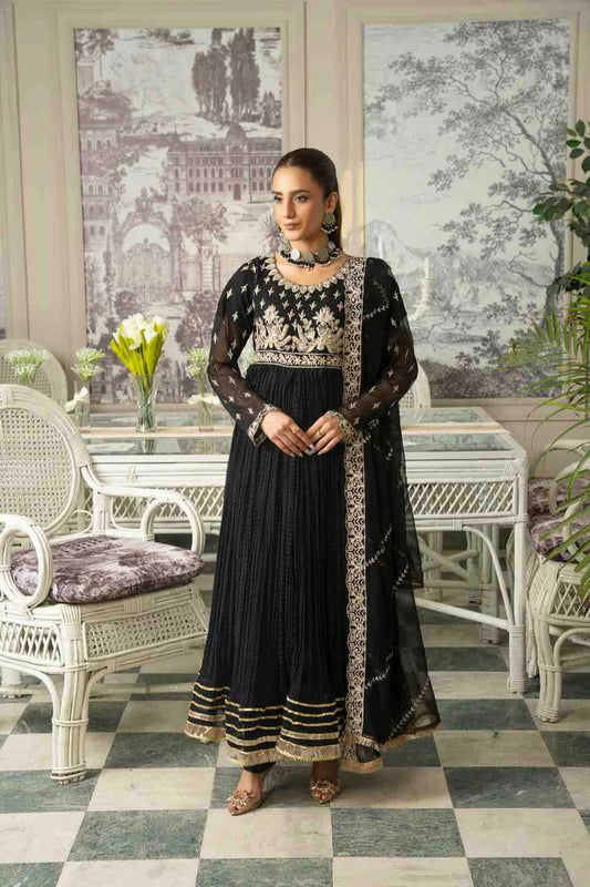 Woman in a black and white embroidered dress standing in a decorated room with white furniture and artwork.