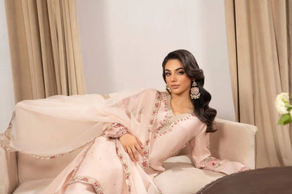 Woman in a pink traditional outfit sitting on a couch with beige curtains in the background