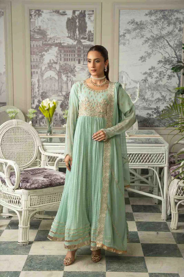 Woman in a light green traditional outfit standing in an elegant room with white furniture and decorative elements.