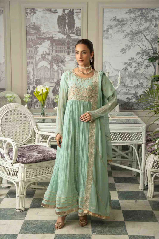 Woman in a light green traditional outfit standing in an elegant room with white furniture and decorative elements.