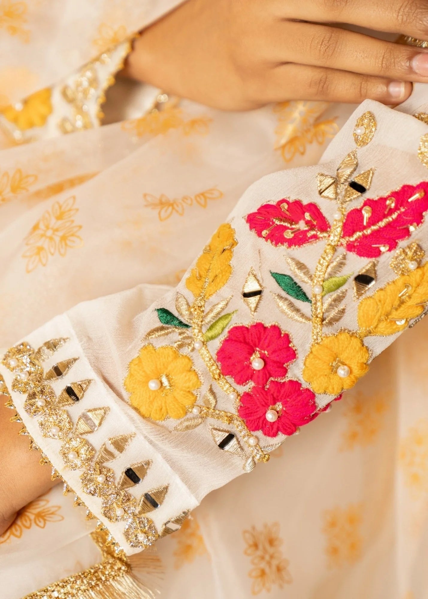 Close-up of a hand holding a phone case with floral embroidery on a light fabric background