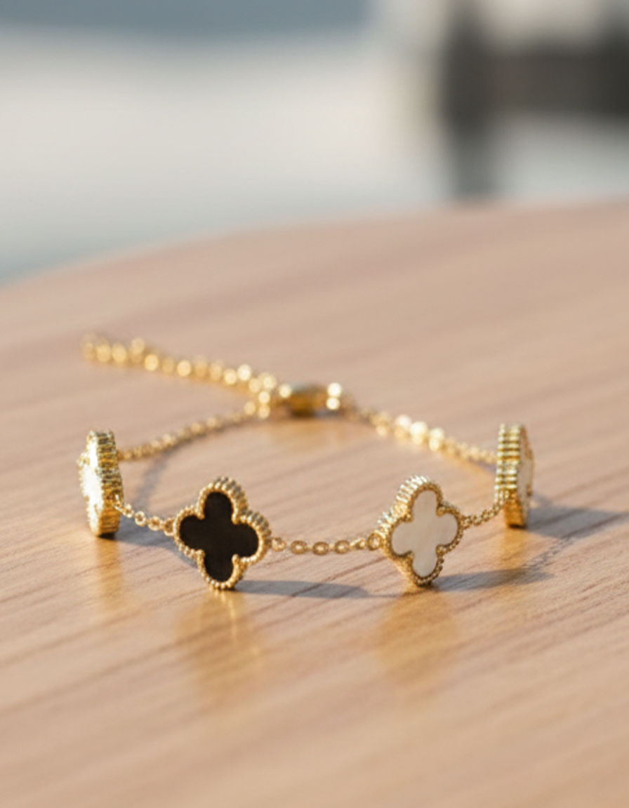Gold bracelet with clover designs on a sandy surface
